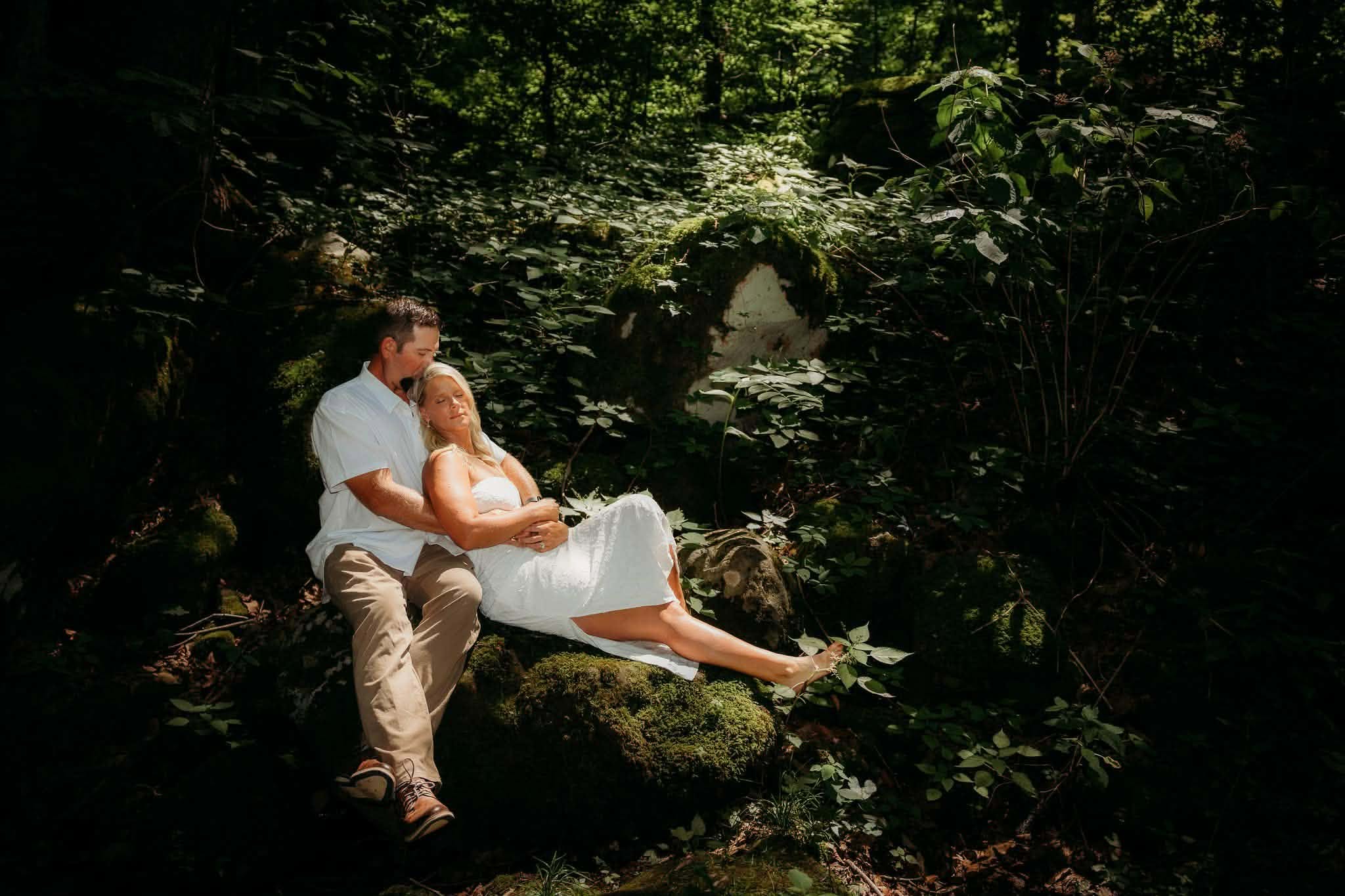 Groom lifting his bride in a shadowed forest clearing