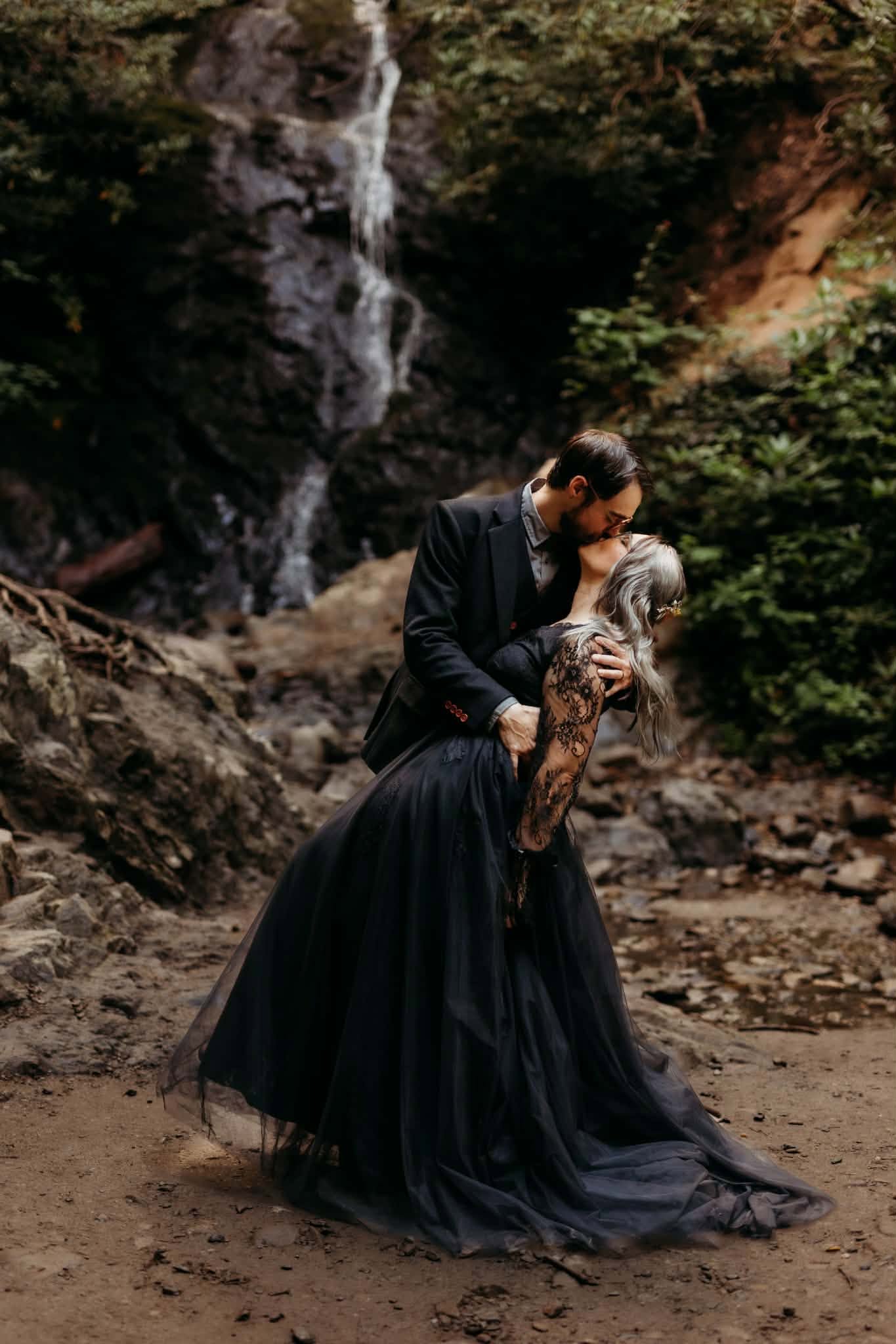 Tattooed couple kissing beside a woodland stream