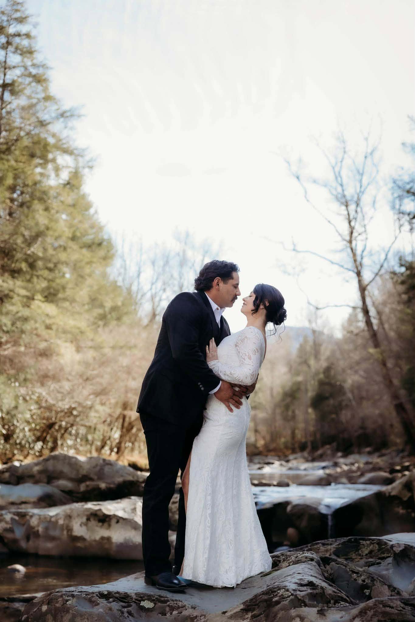 Groom dipping his bride beside a winter creek