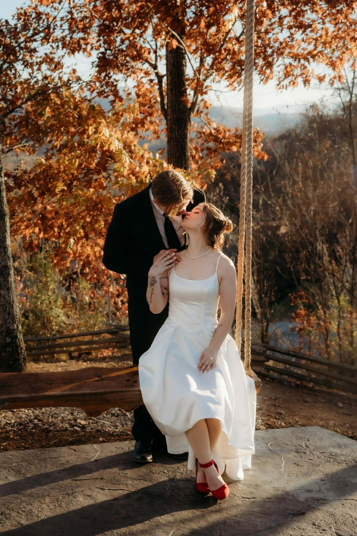 Newlyweds kissing on a wooden bridge in autumn