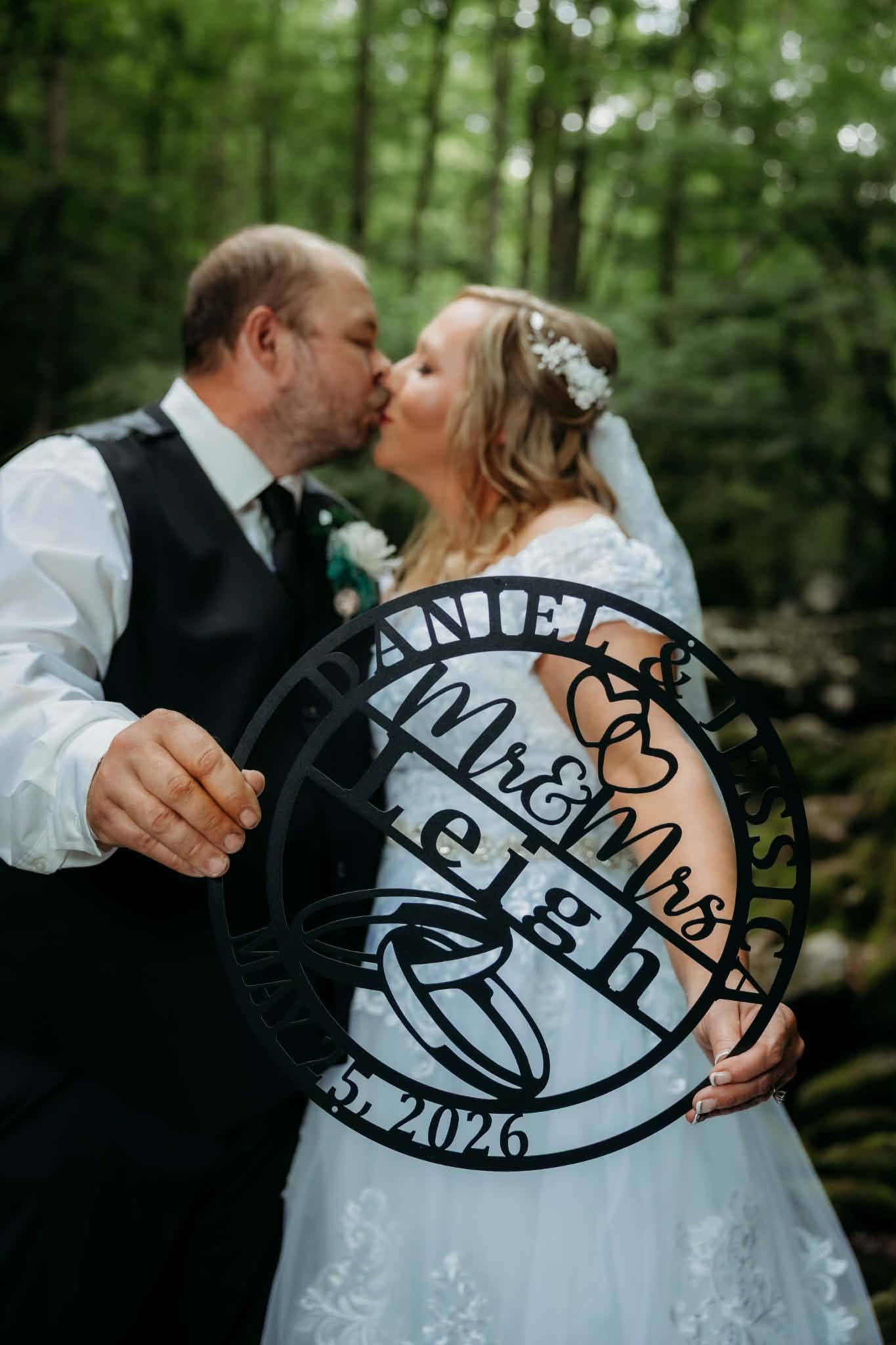 Newlyweds kissing behind their custom wedding sign