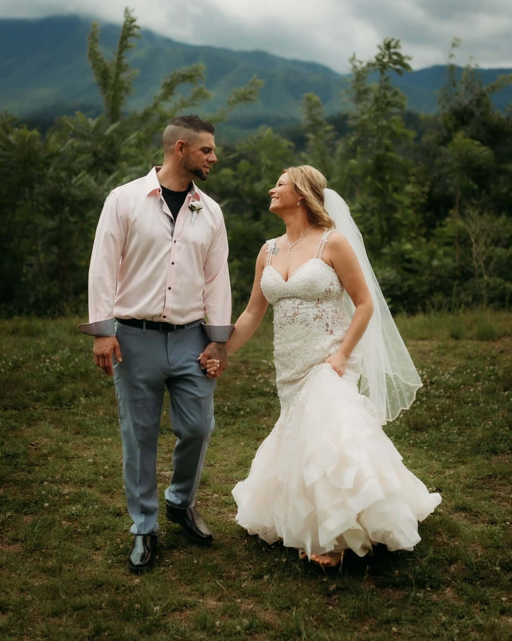 Bride and groom holding hands in a mountain meadow
