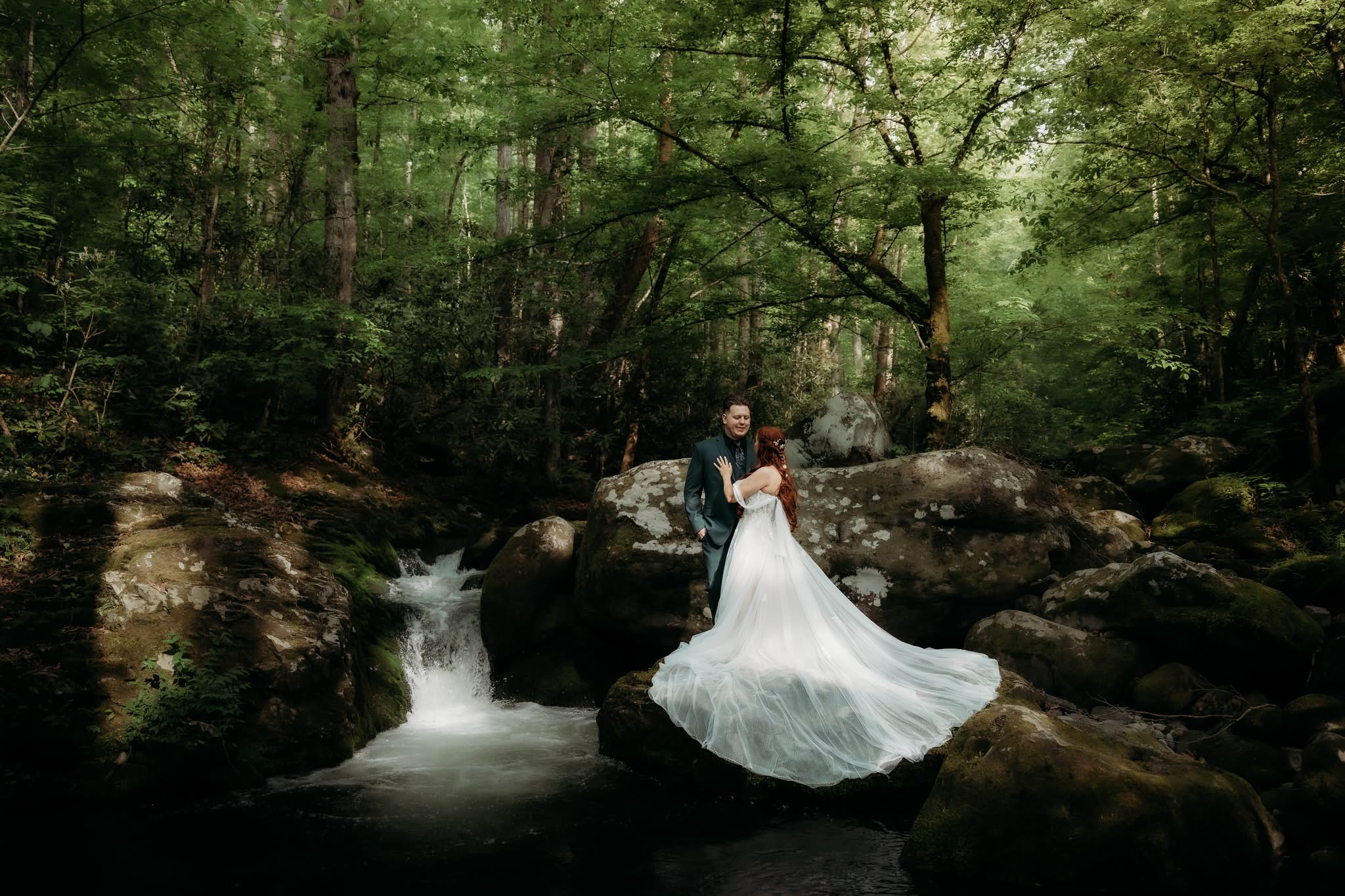 A bride and groom beside a forest stream at Ely’s Mill in Gatlinburg